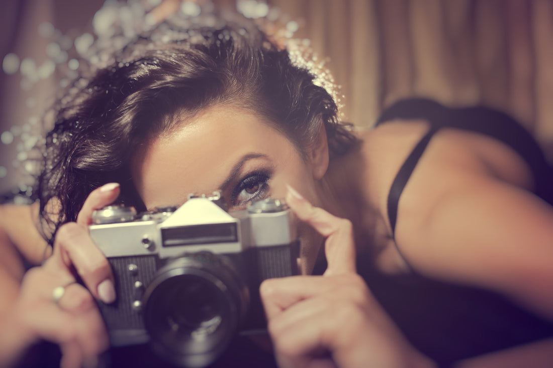 Sensual woman takes a photo of an old camera