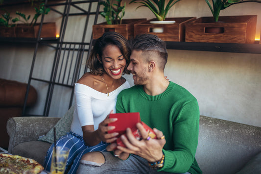 Happy interracial couple sitting in cafe bar. Man giving gift to his girlfriend.